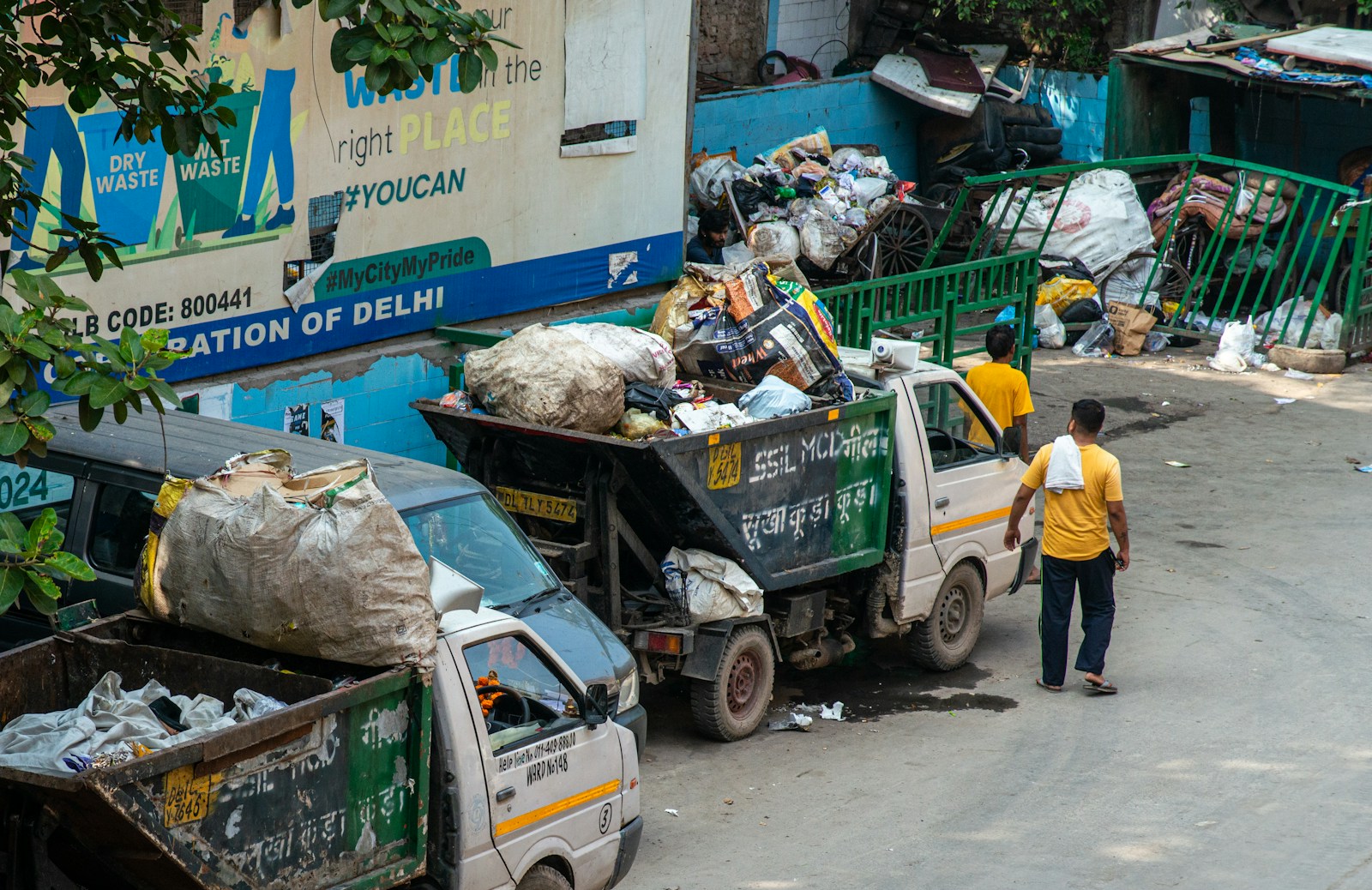 Workers load trash into a garbage truck on a street