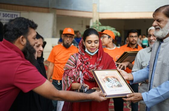 Man presents framed artwork to woman and man