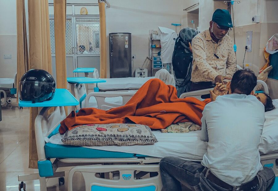 Photo by Anirudh a group of people sitting around a hospital bed