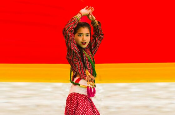 A young girl in traditional clothing dances joyfully dances